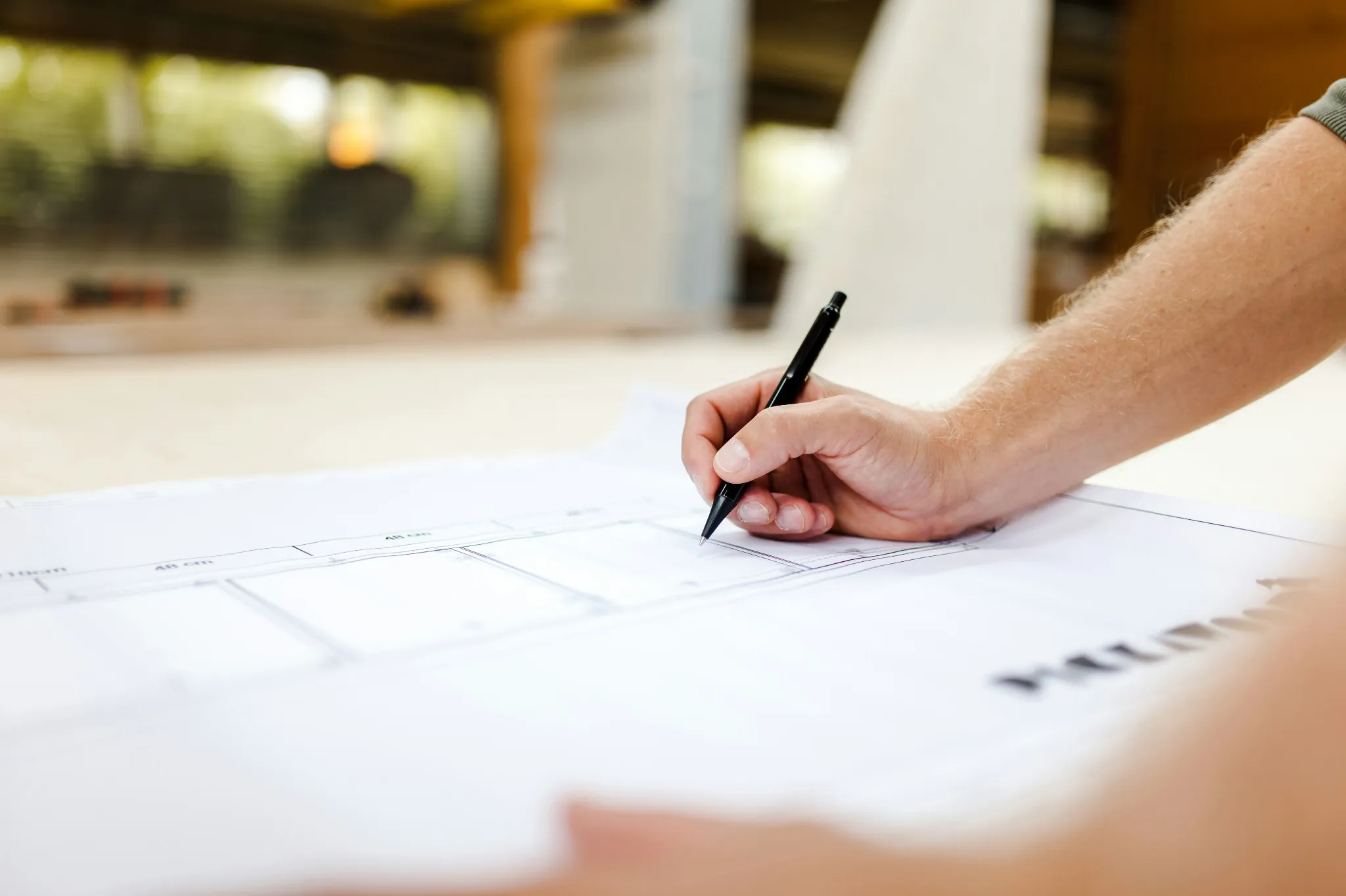 Hand mit Stift über technischen Planunterlagen